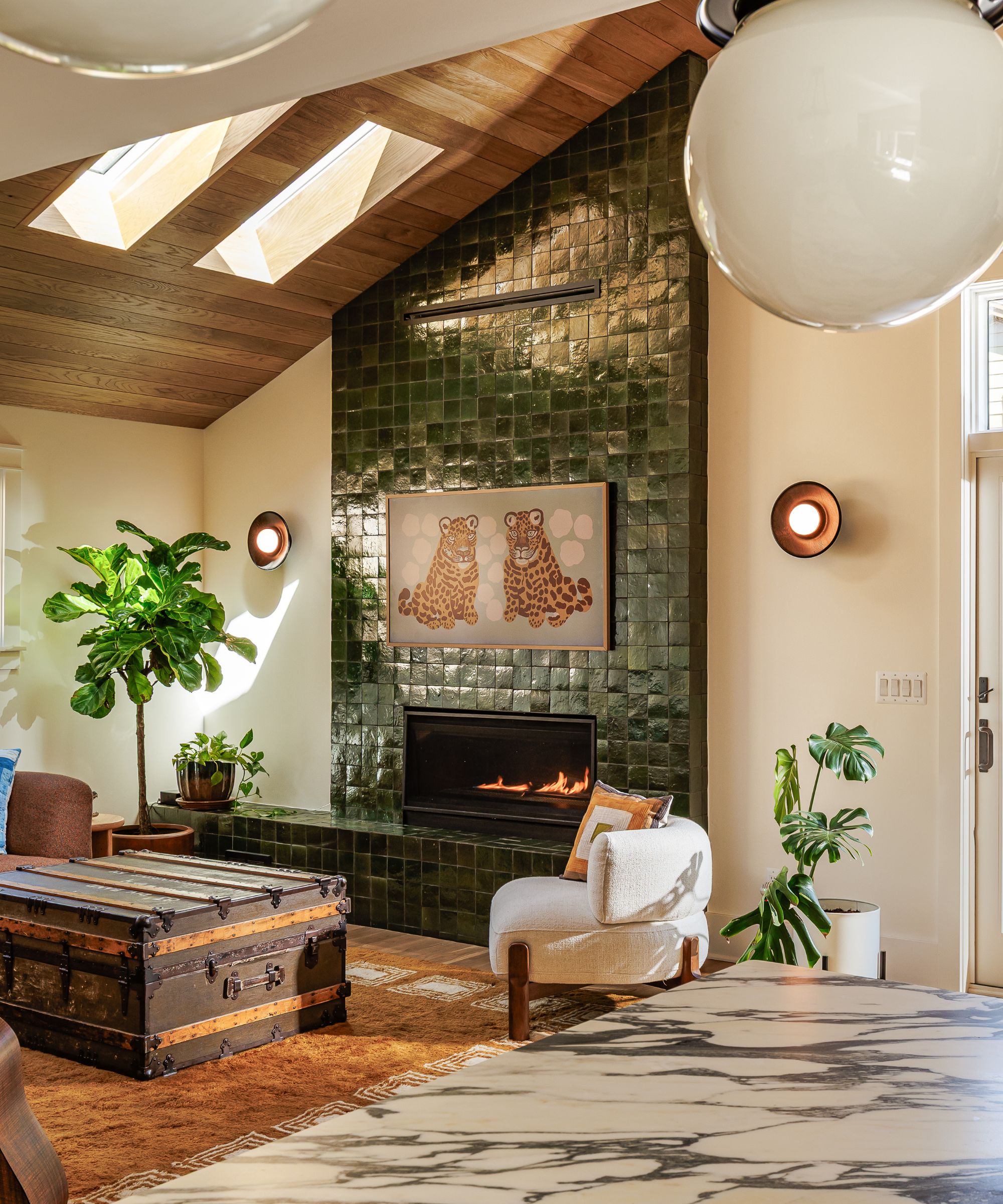 Living room with wooden ceiling and skylights, green tiled fireplace and trunk coffee table