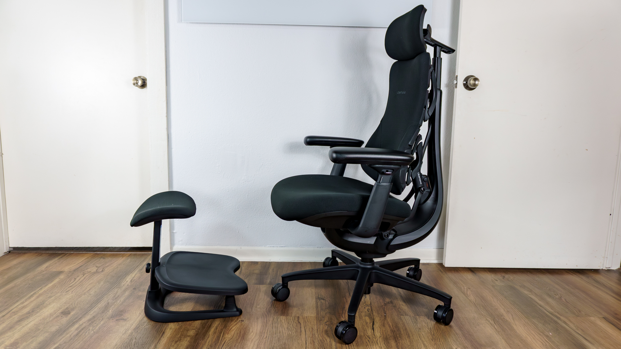 The LiberNovo Omni SE office chair seen from the side with LiberNovo's StepSync footrest in front of it