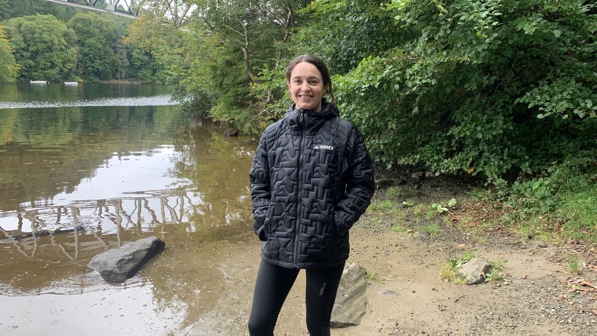 Hiker standing by the river with hands in pockets of puffer jacket