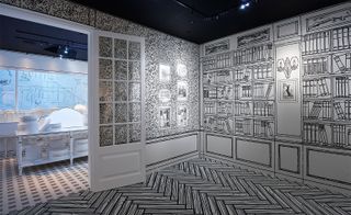 Black and white room at the Mademoiselle Privé exhibition - the wooden flooring has been illustrated along with the bookcase, flowers and images in frames on the wall