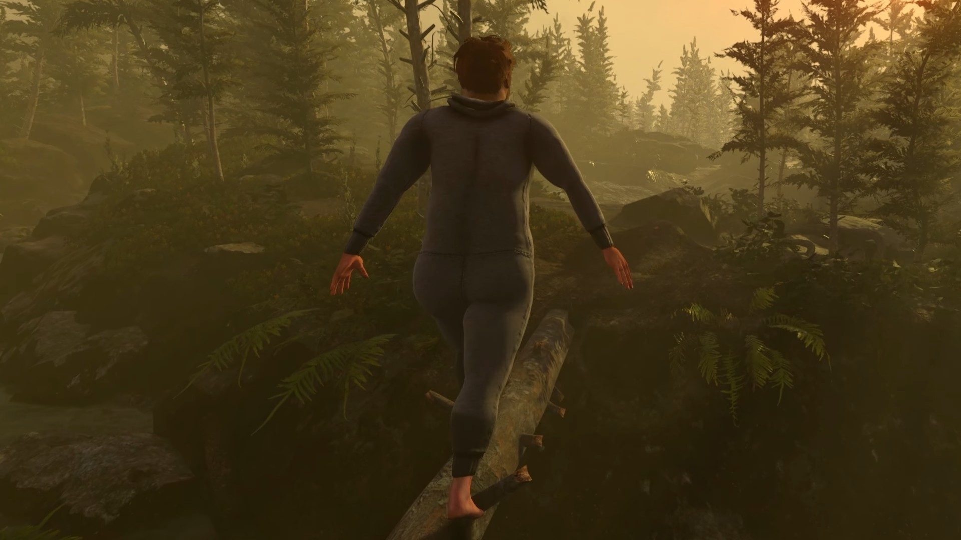 A grown man toddling about, walking down a log balanced over a trench. 