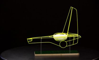 Model of the outline of a futuristic car in neon yellow on a black and wood stand
