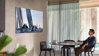 Samsung Q950TS 8K QLED TV hanging on wall while man watches over table