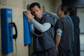 Taron Egerton as prisoner Jimmy in Black Bird standing in a prison on the phone.