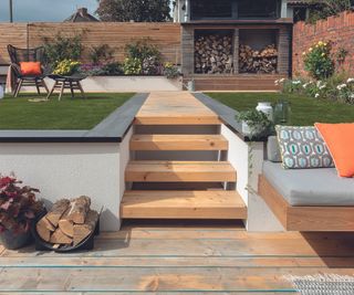 A sunken patio with steps leading up to a lawn area in a garden
