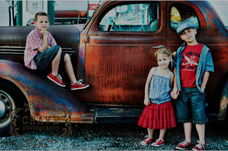 Three children in front of old car
