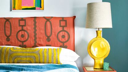 bedroom with burnt orange headboard and yellow lamp