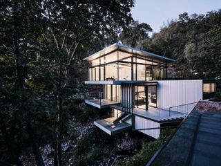 Exterior view of Suspension House spans a creek in the Californian hills