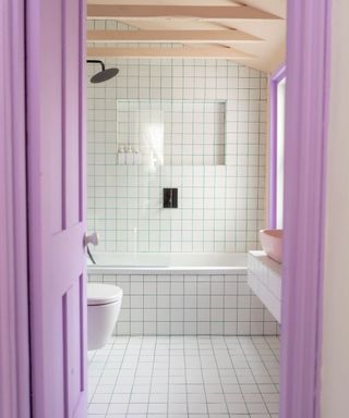 Small white tiled bathroom with purple curtains