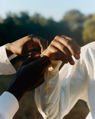 Image of the hands of two figures, one fastening the other's cuff, as seen in Tyler Mitchell's latest publication, I Can Make You Feel Good