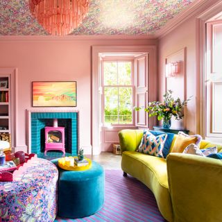 A colour-drenched pink living room with a curved chartreuse sofa and contrasting mismatched cushions on top