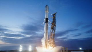 a white and black rocket ignites its engines to lift off from a launch pad under a mostly clear dusk blue sky