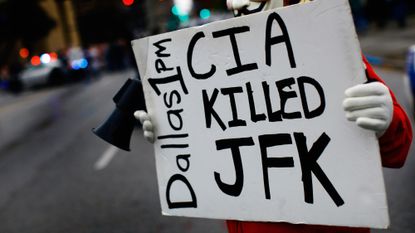 A JFK conspiracy theorist holds up a sign in Dallas, Texas.