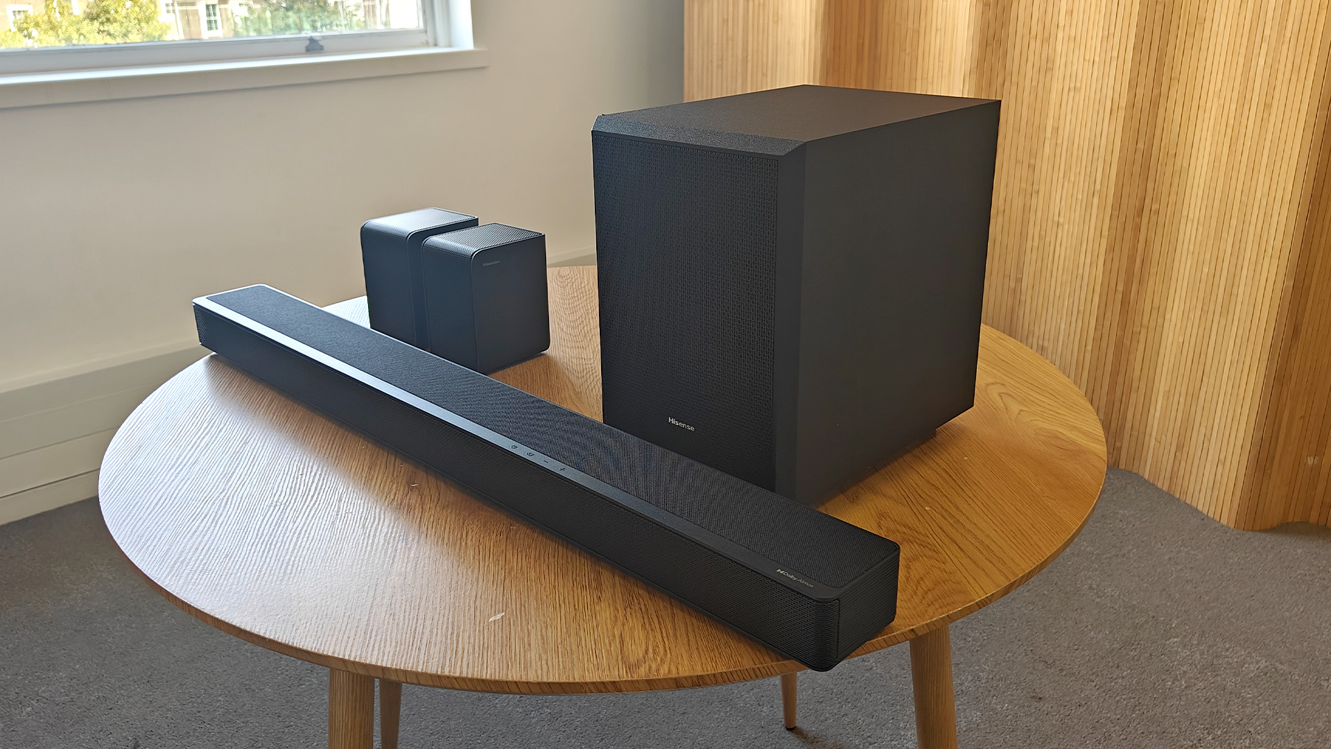 The Hisense AX5125H Dolby Atmos soundbar system, pictured on a round, wooden table