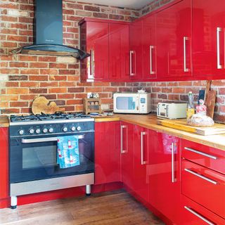 red gloss kitchen with brick wall