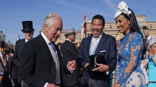 King Charles III speaks to Lionel Richie and Lisa Parigi during the Garden Party at Buckingham Palace ahead of the coronation of the King Charles III and the Queen Consort at Buckingham Palace