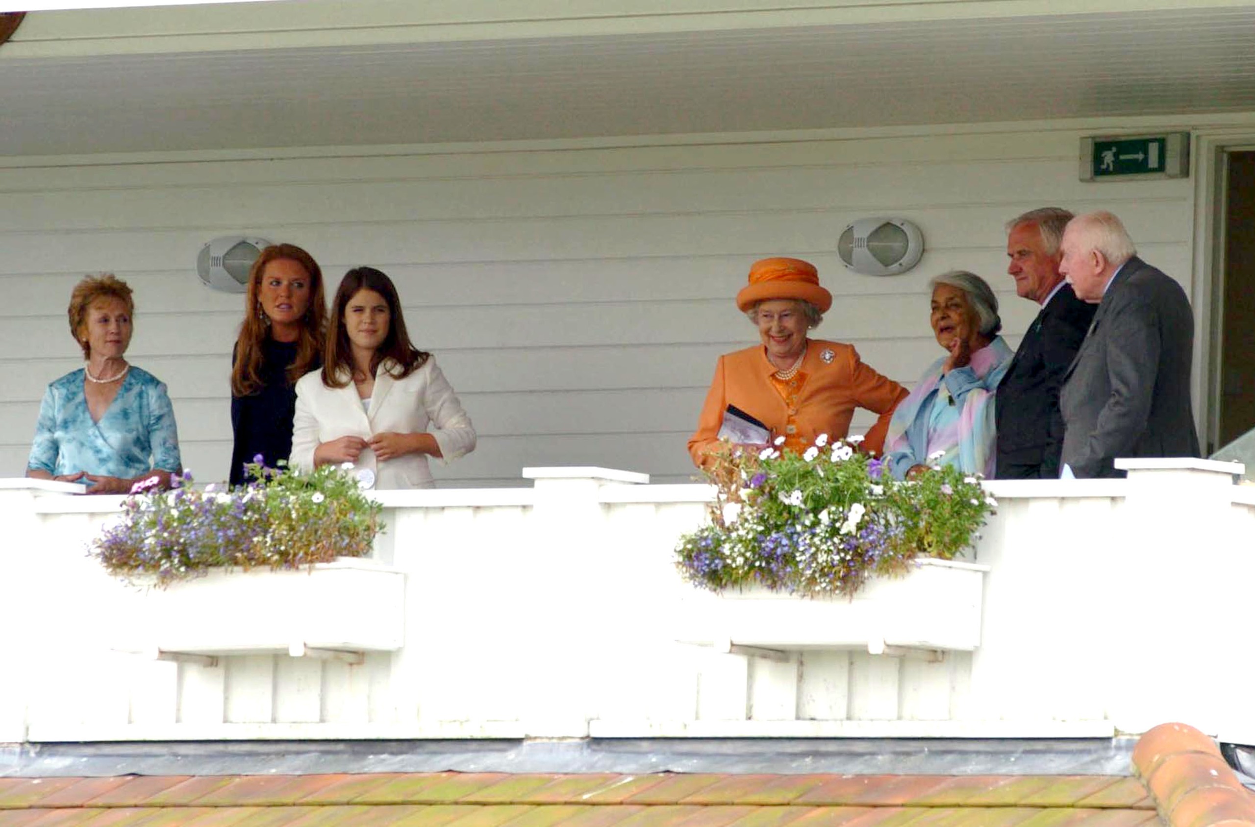 Queen Elizabeth, Princess Eugenie and Sarah Ferguson standing on a white balcony with guests at the Cartier International Day Polo Coronation Cup 2004