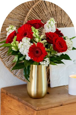 A bouquet of red and white flowers in a gold vase