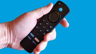 The Amazon Alexa Remote in a hand over a blue background.