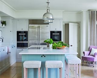 neutral kitchen with aqua island, chrome pendant lights and pink armchair