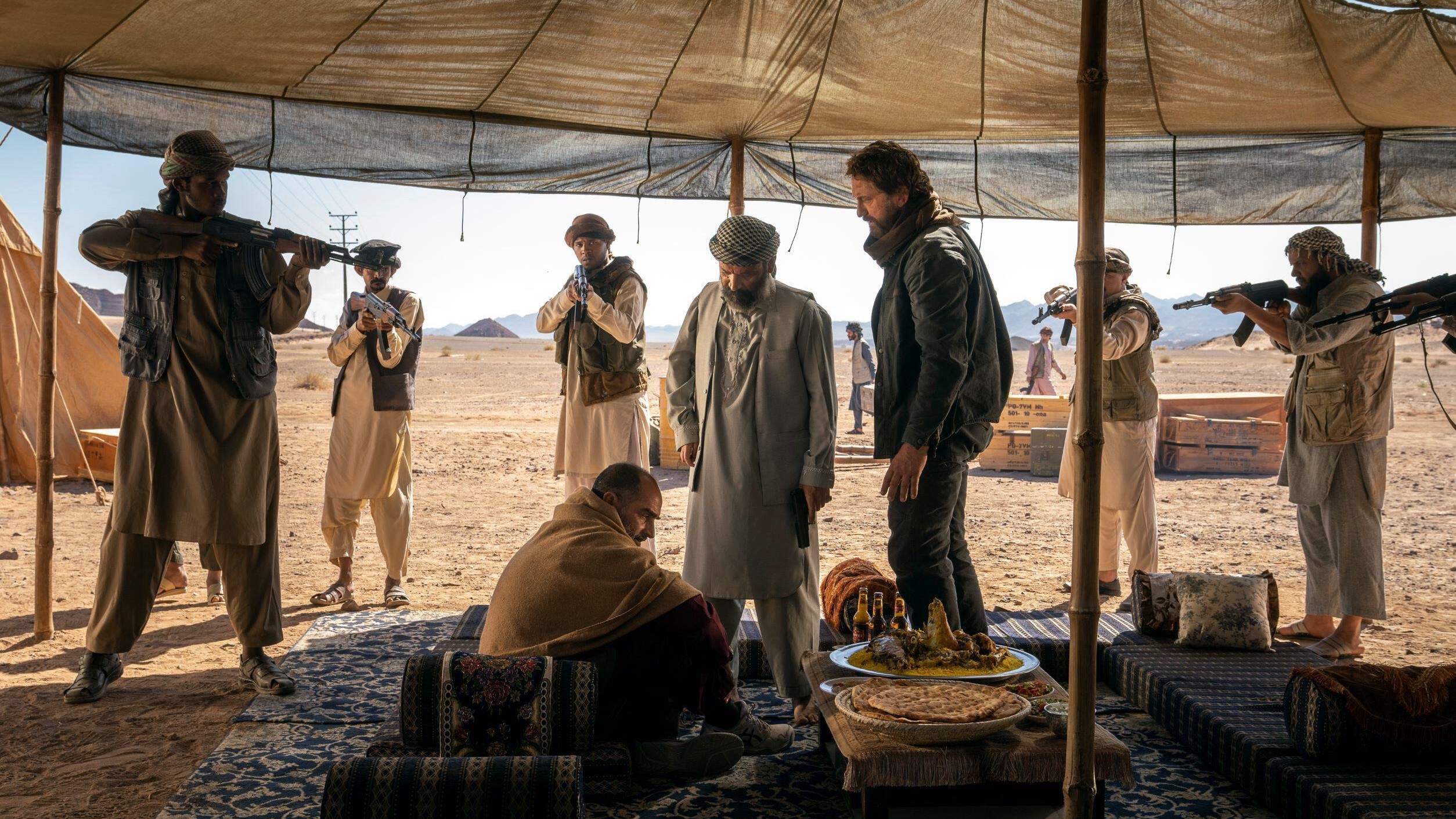 Tom (Gerard Butler) surrounded by men armed with rifles in a scene from "Kandahar" (2023)