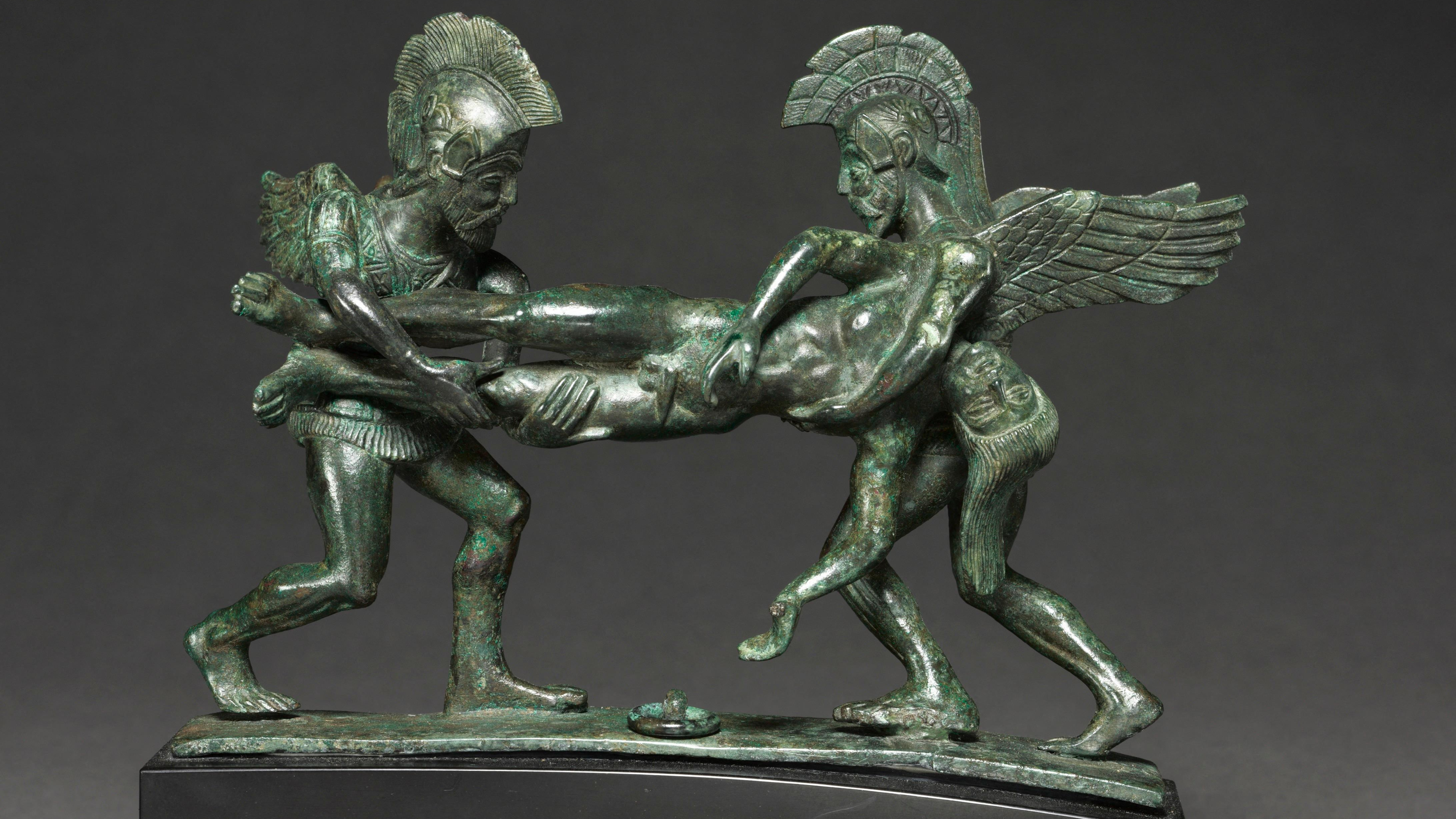 two helmeted bronze figures hold a horizontal corpse between them
