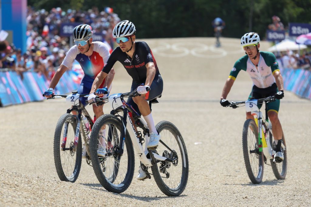Britain's Thomas Pidcock (C), France's Victor Koretzky (L) and South Africa's Alan Hatherly (R) compete in the men's cross-country mountain biking event during the Paris 2024 Olympic Games in Elancourt Hill venue in Elancourt, on July 29, 2024. (Photo by Emmanuel DUNAND / AFP)