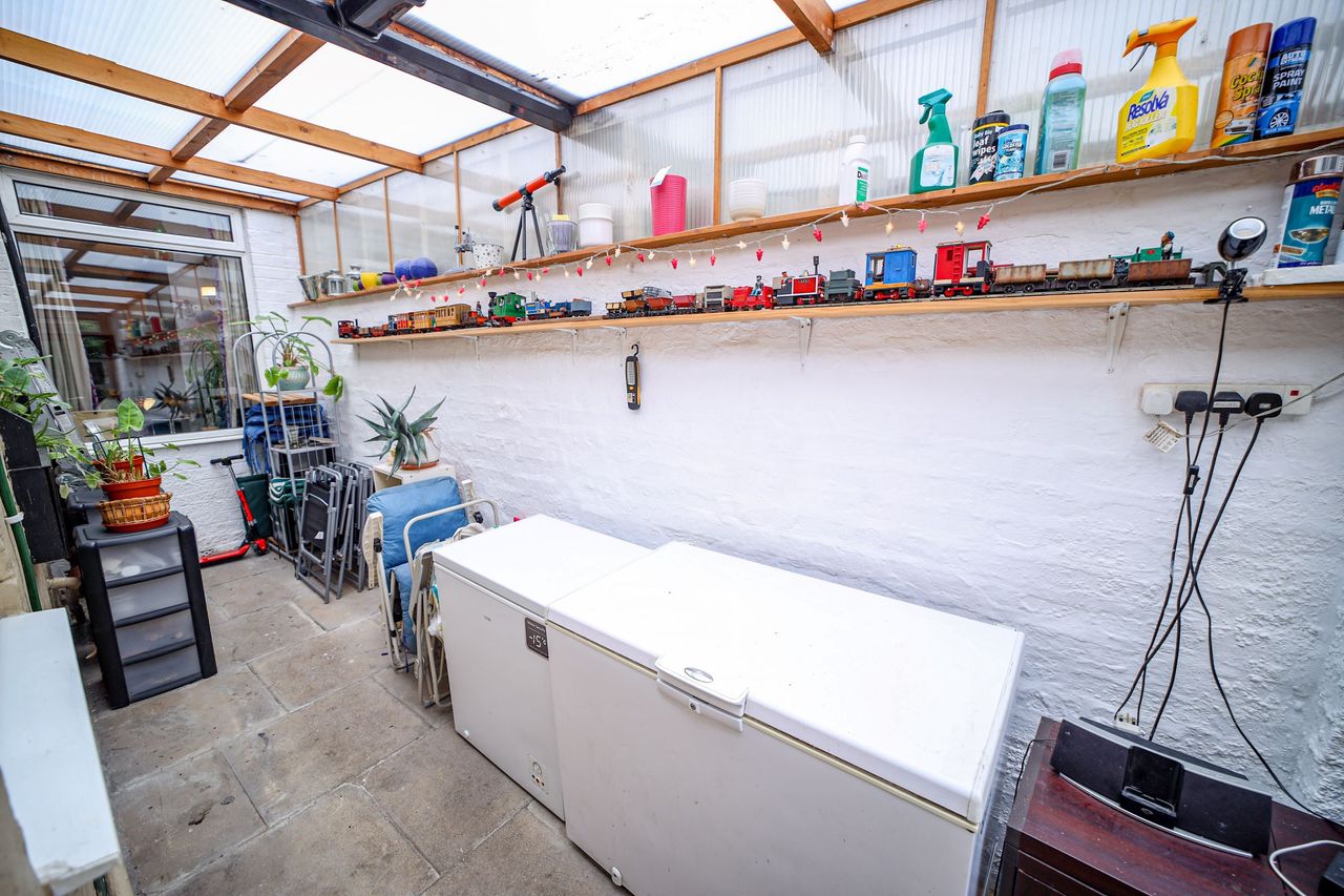 The utility room next to the kitchen shows wooden shelving and washers and dryers under a wooden beam roof and white tarpaulin