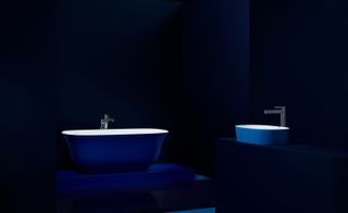 Blue 'Amiata' collection volcanic limestone bathtub and basin by House of Rohl against dark background