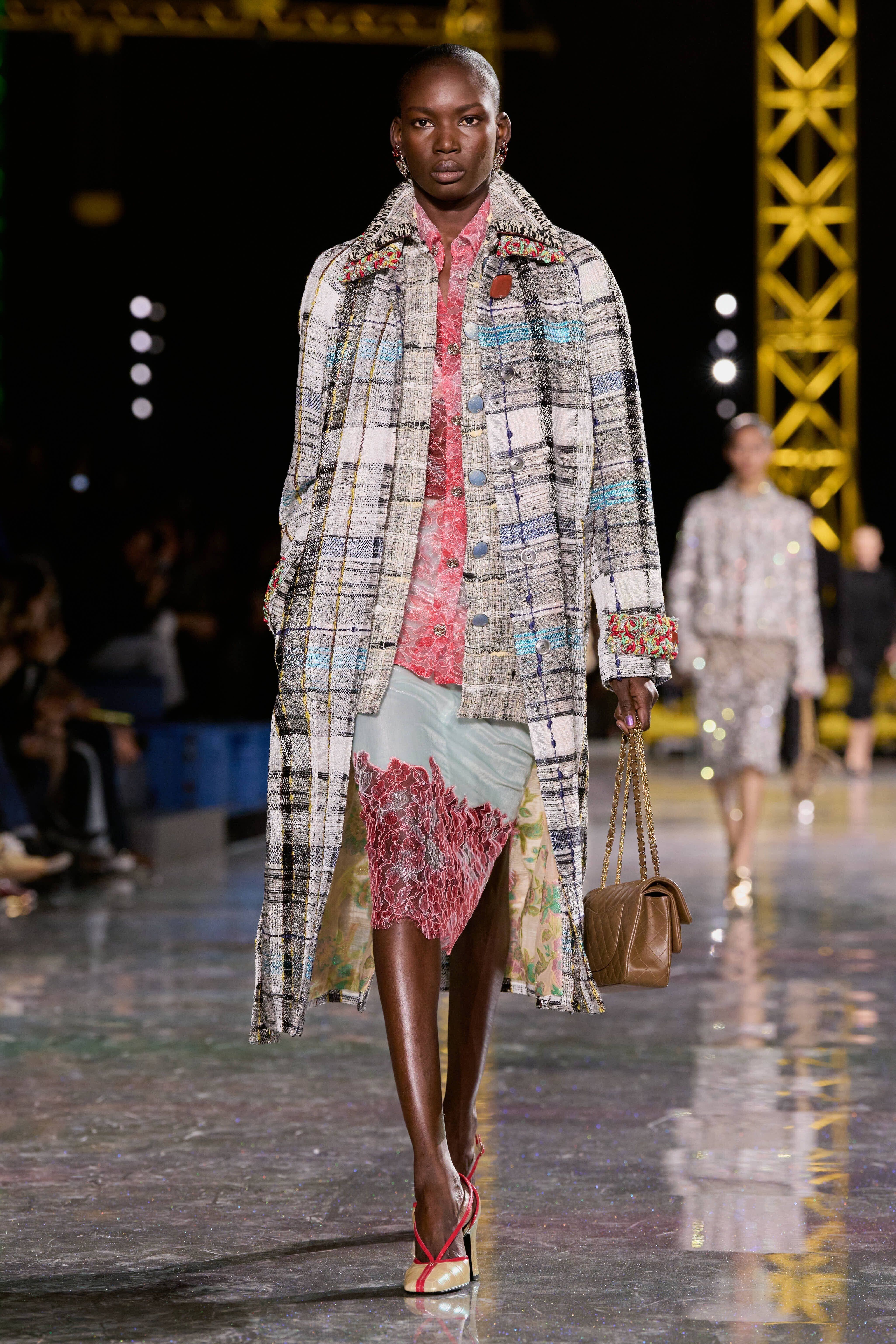 a model on the runway at chanel aw26 wearing a dress coat and lace