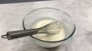 A whisk in a bowl of cream and milk for making ice cream