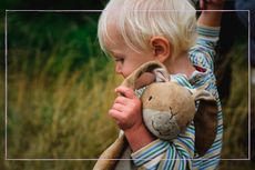 Toddler walking hand in hand with parent while holding on to stuffed rabbit toy
