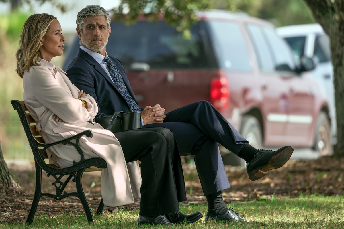 maria bello as Belle Buckley and Dave Annable as Wes Larsen sitting on a bench outside talking in the waterfront