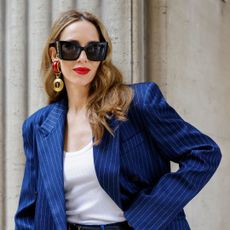 best long lasting lipsticks - Alexandra Lapp is seen wearing a pinstripe blazer and pants in navy by The Frankie Shop, a Colorful Standard tank top in white, a Hermes Kelly 25 bag in red, a YSL logo belt from Saint Laurent, Saint Laurent ear clips in red and Saint Laurent logo sunglasses in black - getty images 2071897395