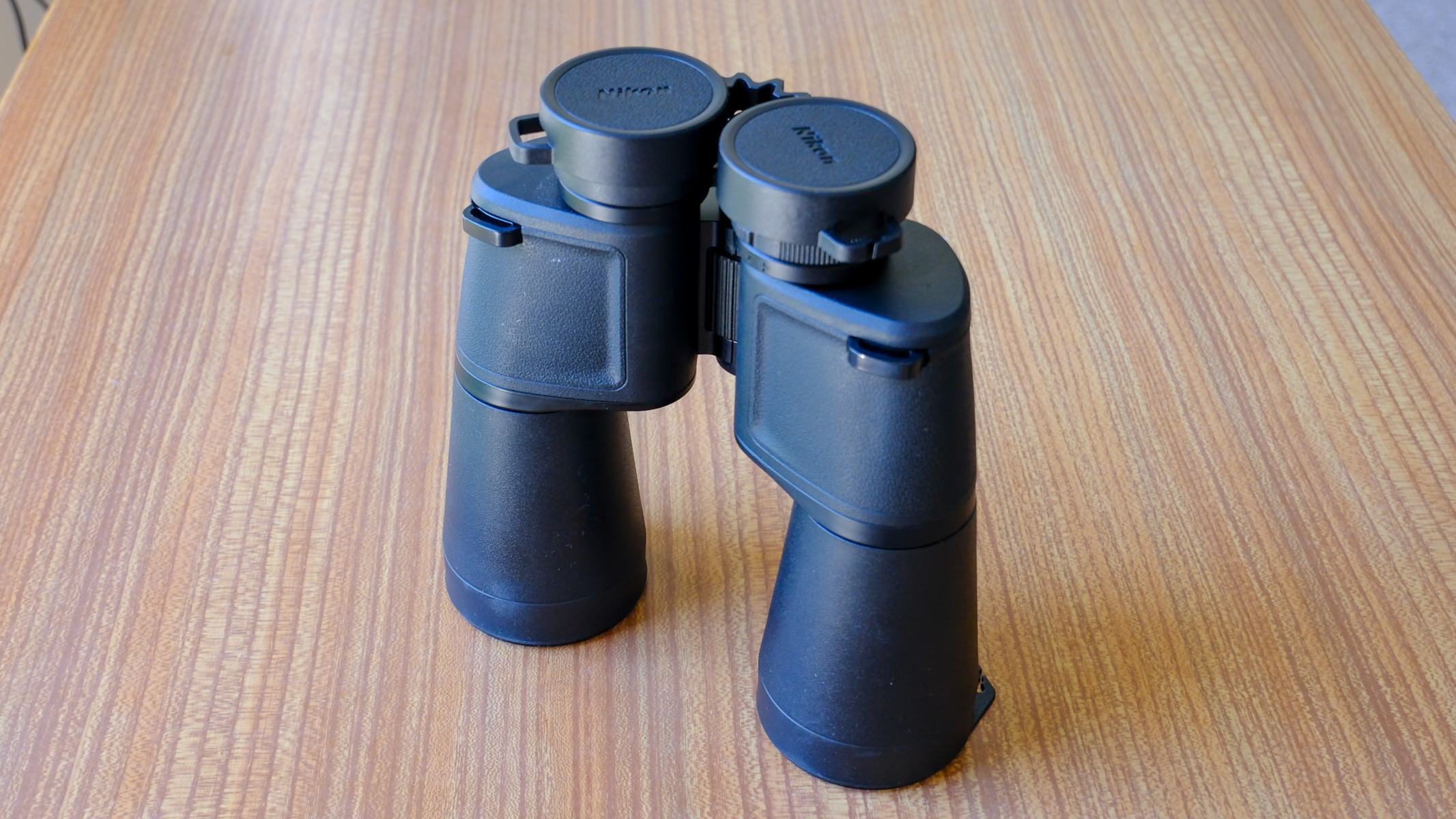 The Nikon Action 16x50 binoculars stood up on a wooden table.