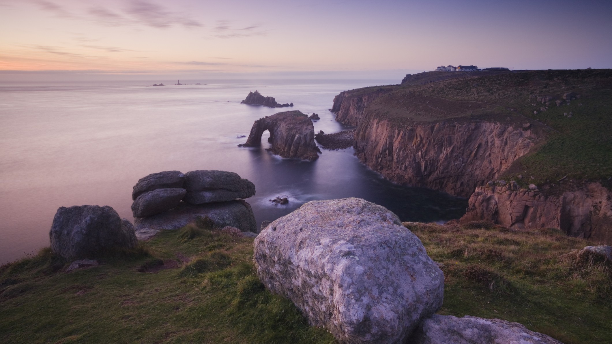 striking cliffs meet the sea. there is a rock with an arch.