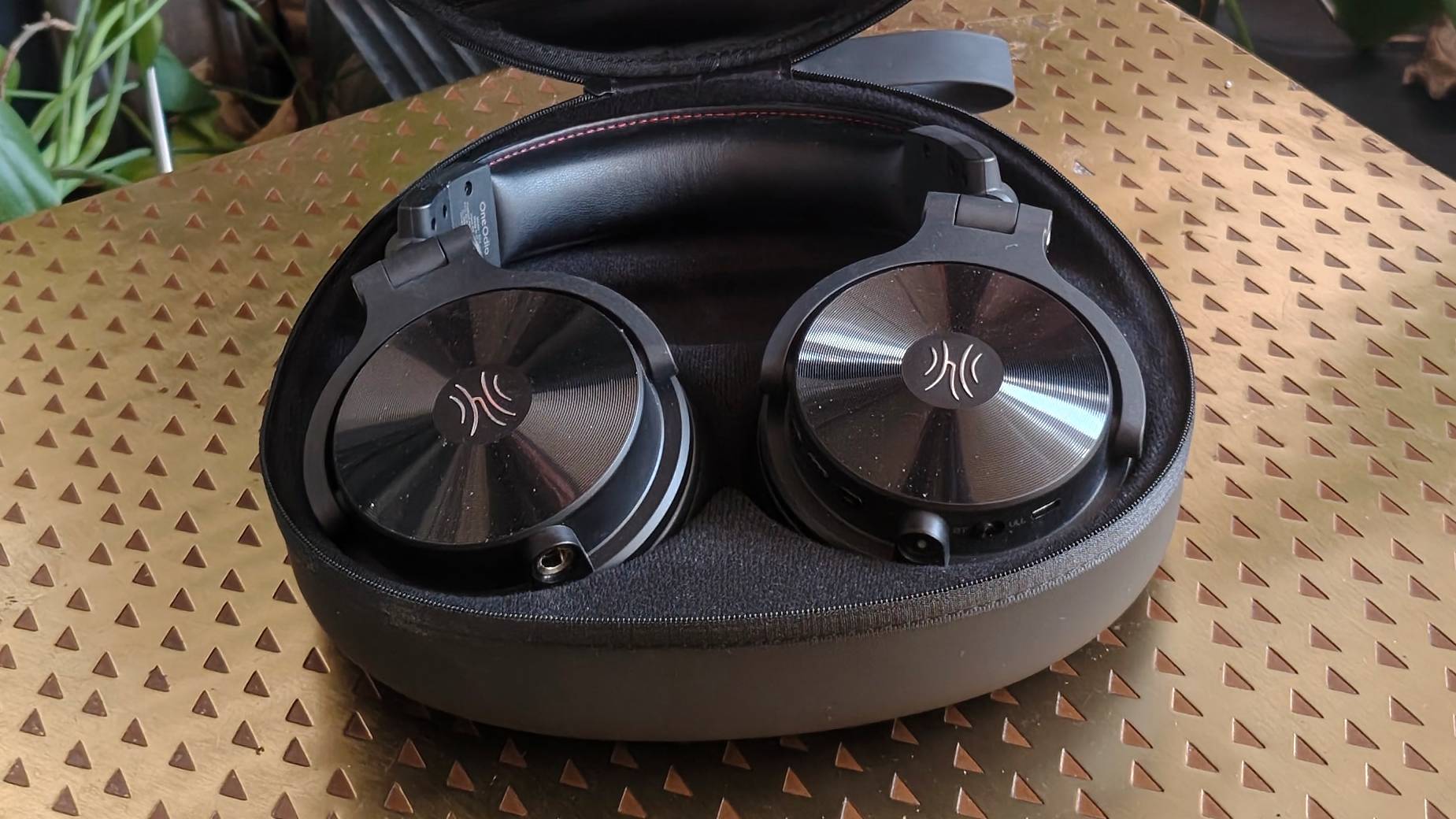 The OneOdio Studio Max 2 in their case on a bronze table.