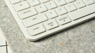 a close up shot of a white wireless bluetooth keyboard resting on a clean white table