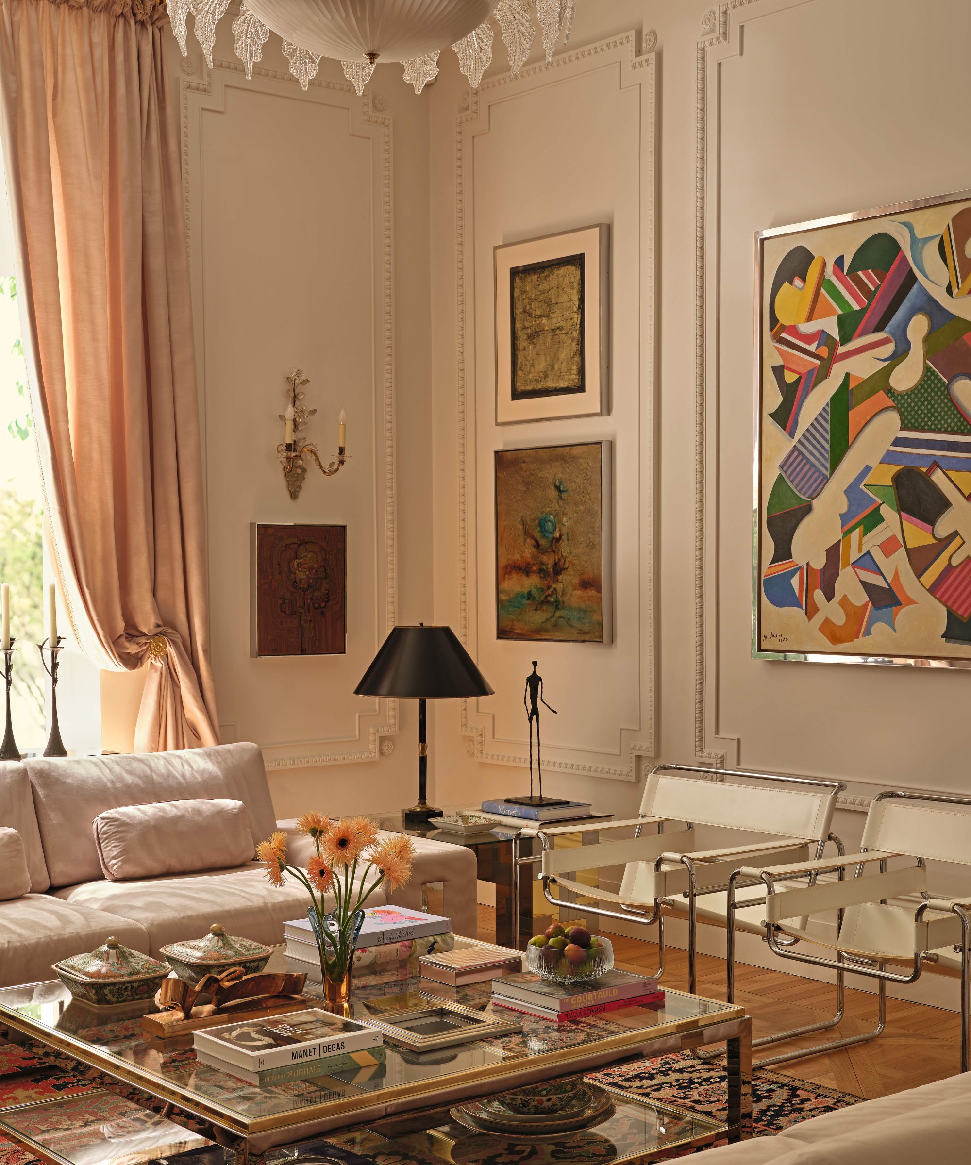a pale pink victorian living room with ornate molding and mid century furniture