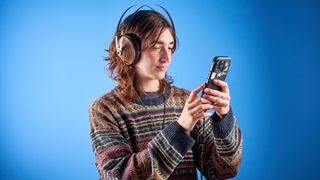 the meze 99 classics 2nd gen headphones with walnut finishes and gold touches against the blue tom's guide background