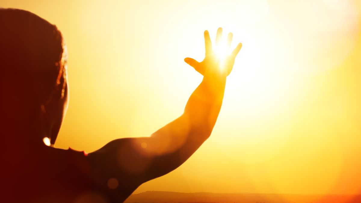 Young woman reaching for the sun