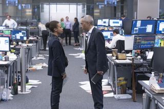 Harper (Myha'la Herrold) and Eric (Ken Leung) stand on the trading floor at Pierpoint in a scene from Industry. The room behind them is in disarray with papers all over the floor, and they appear to be having an intense and heated conversation.