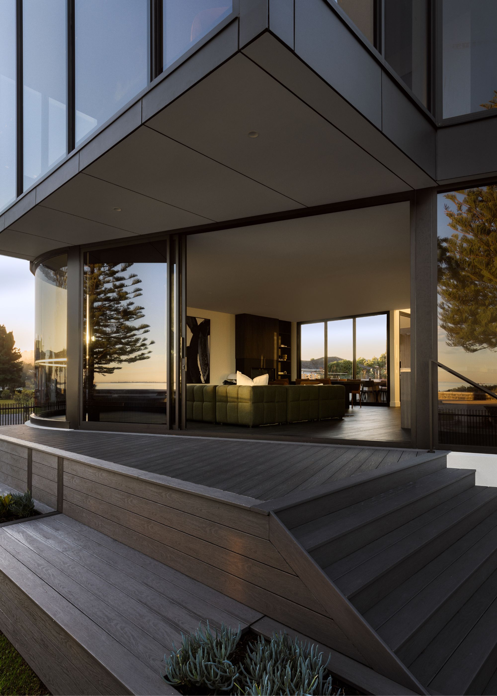 The exterior of a home with decking laid outside in the backyard. There is a view from the distance of the inside of the home.