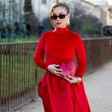 woman walking down the street wearing a red dress and holding a heart-shaped bag - Romantic perfumes