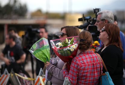 Mourners hold flowers outside of the Inland Regional Center in San Bernardino, California.