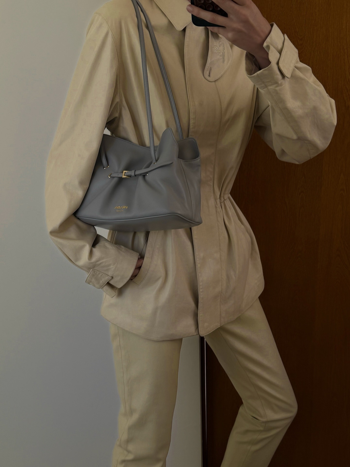 Elsa Hosk takes a mirror selfie wearing the Prada Dada bag in grey with a butter yellow jacket and trousers.