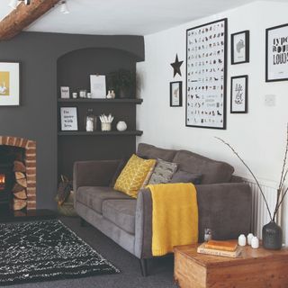 A small living room with a white and charcoal wall and a charcoal sofa