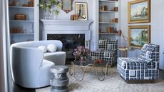 blue living room with matching blue curved sofa, fireplace, round coffee table and open bookshelves