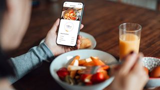 woman using an app to track her macros at breakfast