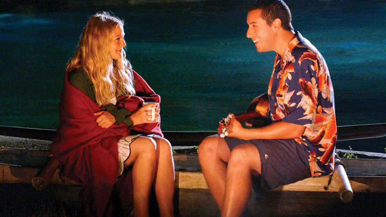 Adam Sandler and Drew Barrymore sitting around a fire.